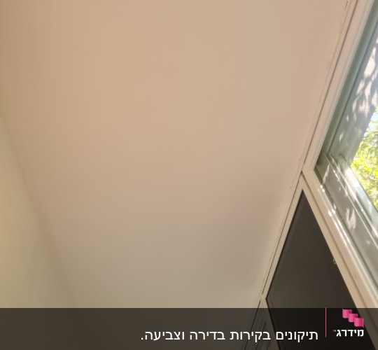 תקרה צבועה בלבן ליד חלון עם אור שמש